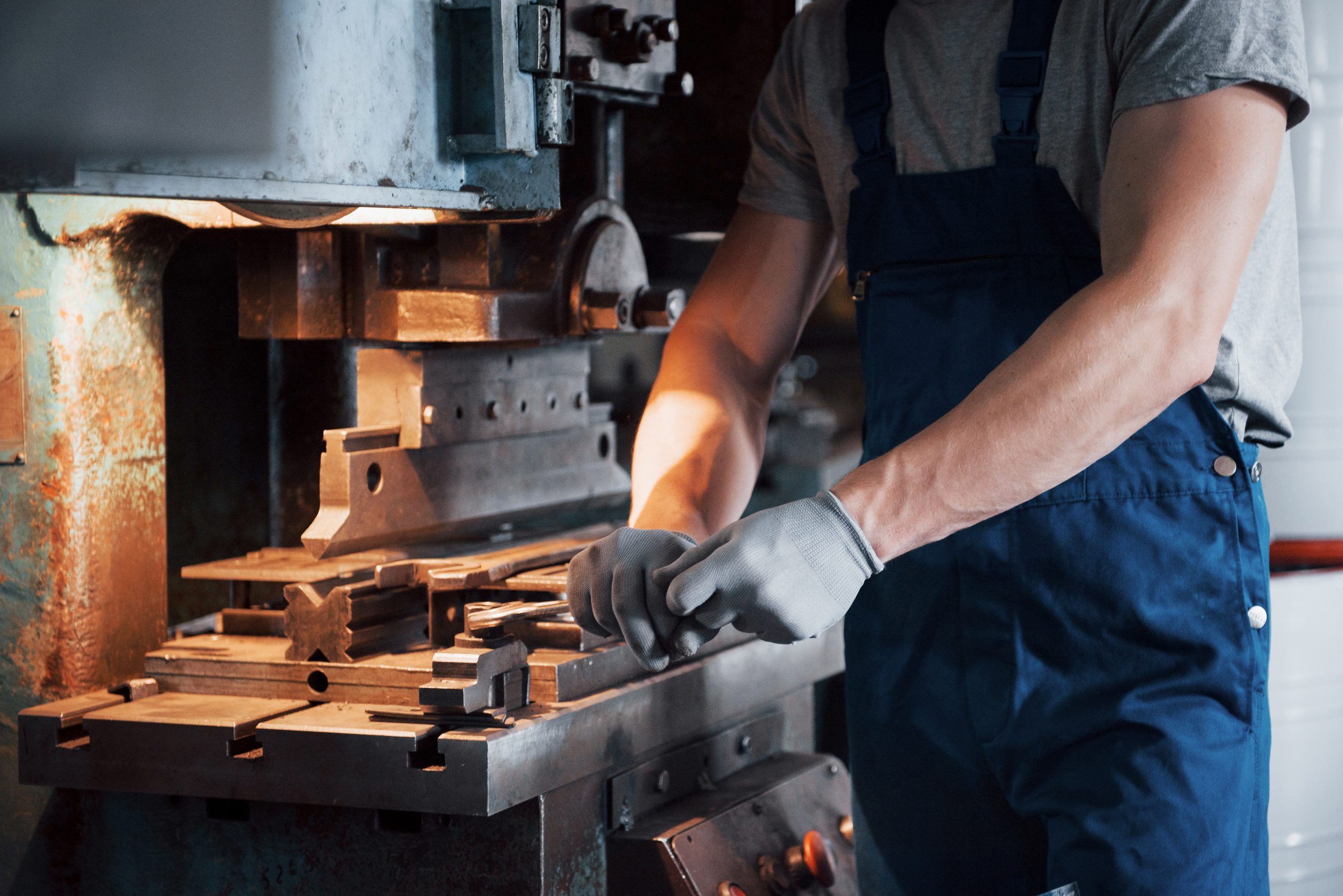 Portrait of a young worker in a hard hat at a large metalworking plant. The engineer serves the machines and manufactures parts for gas equipment